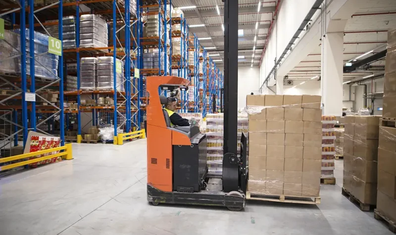 trabajador-industrial-en-carretilla-elevadora-operativa-uniforme-de-proteccion-en-un-gran-centro-de-distribucion-de-almacen